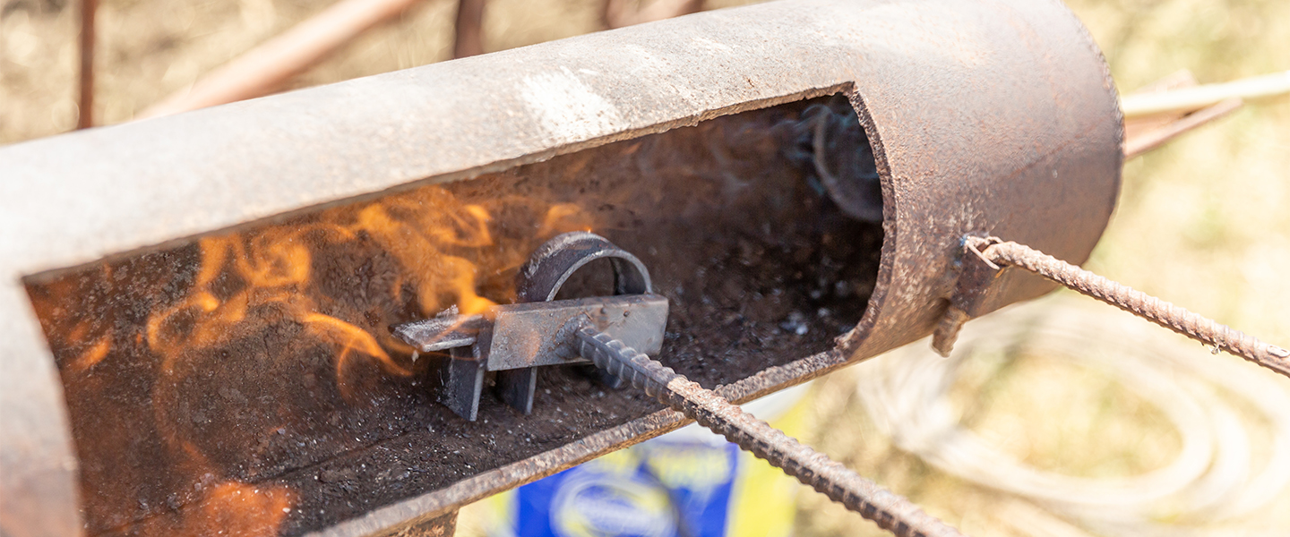 Person heats branding tool in fire